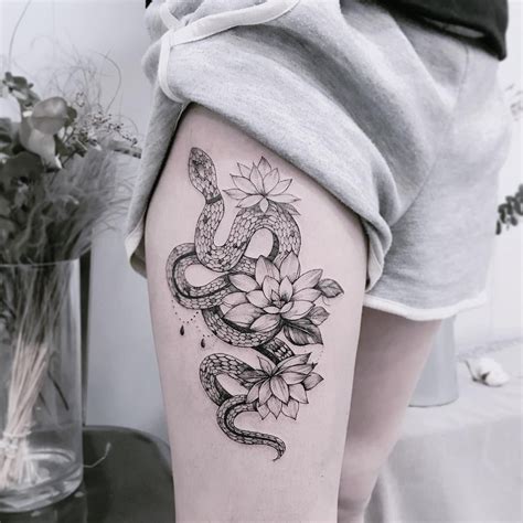 A Woman S Thigh With A Snake And Flowers Tattoo On It