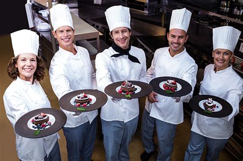 Happy Chefs Presenting Their Dessert Plates In Commercial Kitchen