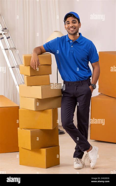 Delivery boy in uniform standing with leaning on cardboard boxes Stock ...