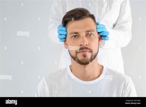 Doctor Examining Mature Man Face Before Cosmetic Surgery On White