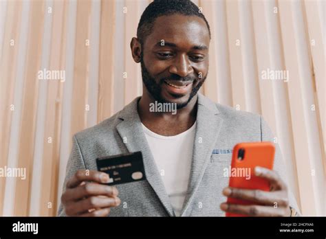 Happy African Businessman In Suit Holding Credit Card And Mobile Phone