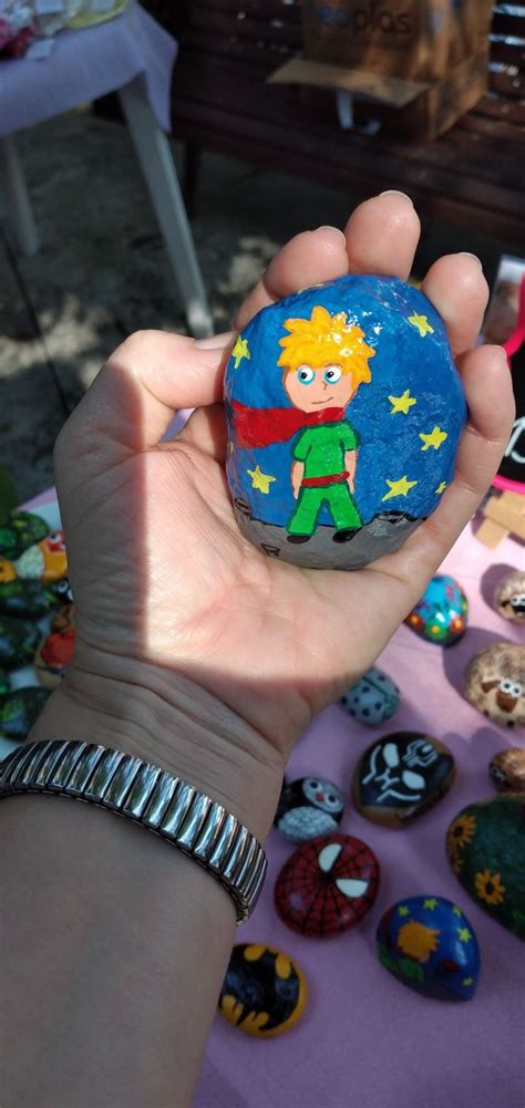 A Hand Holding A Rock With A Cartoon Character Painted On It