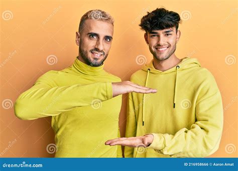 Homosexual Gay Couple Standing Together Wearing Yellow Clothes Gesturing With Hands Showing Big
