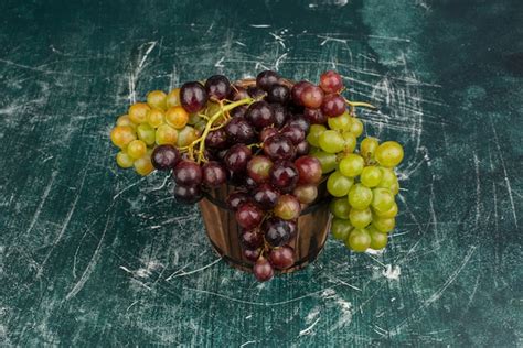 Un racimo de uvas verdes y negras sobre la mesa de mármol Foto Gratis