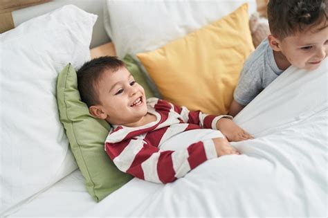 Dos niños sonriendo confiados acostados en la cama en el dormitorio