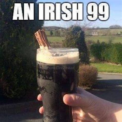 A Person Holding Up A Tall Glass Filled With Beer Next To A Road And Trees