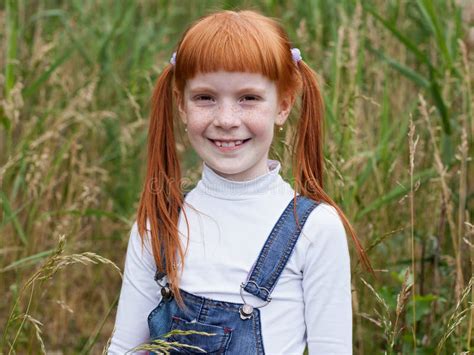 La Petite Fille Rousse Avec Des Taches De Rousseur Sourit Brillamment