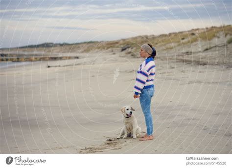 Brünette Frau mittleren Alters am leeren Strand mit ihrem Labrador