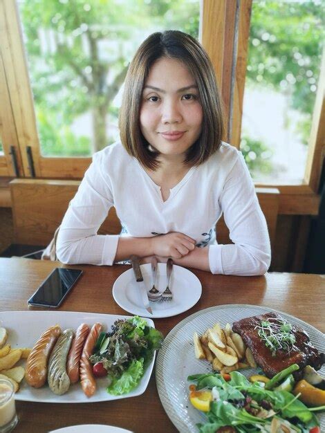 Premium Photo Portrait Of Smiling Woman Sitting On Chair With Food On Table