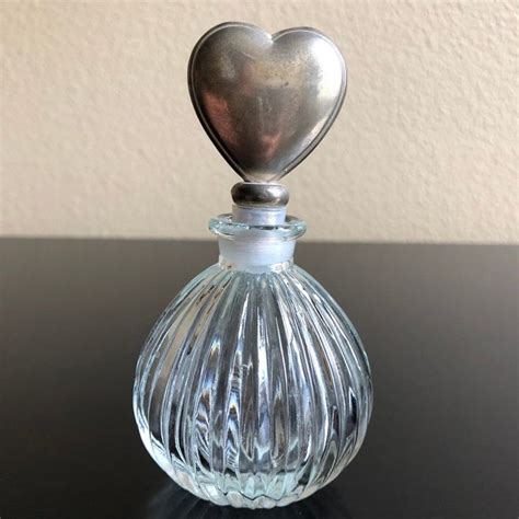 A Small Glass Bottle With A Heart On Its Top Sitting On A Table