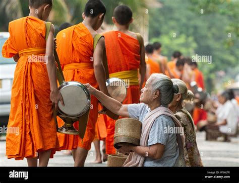 Laotian People Making Offerings To Buddhist Monks During Traditional