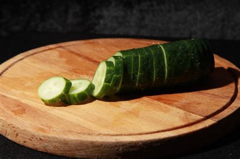 Premium Photo A Sliced Cucumber On A Wooden Cutting Board