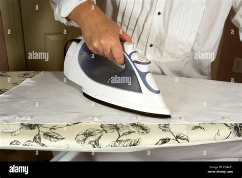 Woman Ironing A White Shirt With A Steam Iron On An Ironing Board Stock