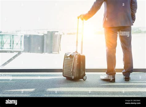 Portrait Of Mature Businessman Standing With His Suitcase While Looking