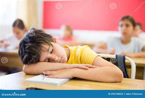 Tired School Boy Sleeping In Classroom During Lesson Stock Photo