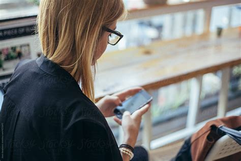 Blonde Woman Using Her Phone At The Coffee Shop By Stocksy Contributor Jovo Jovanovic Stocksy