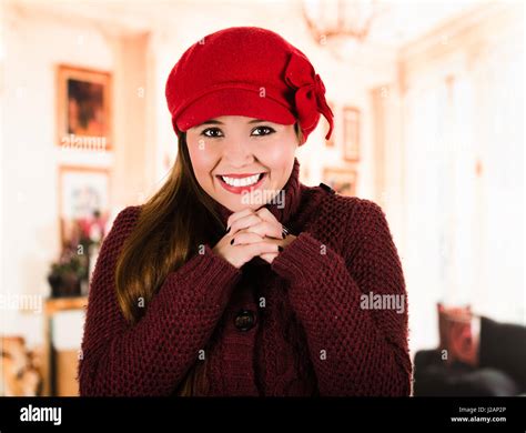 Pretty Young Brunette Woman Wearing Red Sweater And Beenie Folding Hands Together Smiling