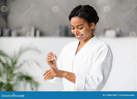 Smiling Beautiful Black Woman Applying Moisturising Serum On Her Hand At Home Stock Image