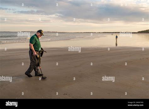 Man Using A Metal Detector To Search For Lost Treasure On A Beach Stock