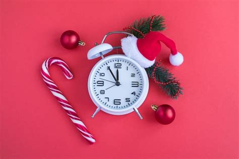 Premium Photo White Alarm Clock With Christmas Santa Hat On The Red