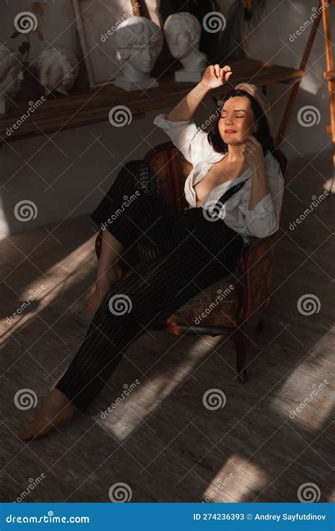 Beautiful Relaxed Brunette Woman In A Chair In The Rays Of The Sun From