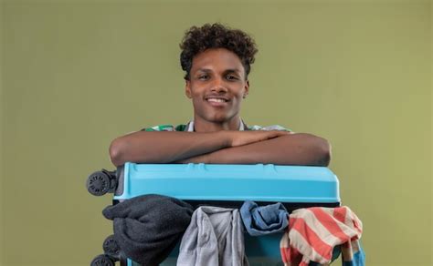 Jeune homme afro américain voyageur debout avec une valise pleine de