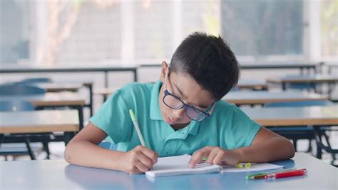 V Deo Gratis Ni O Alumno Latino Enfocado Con Gafas Escribiendo En Papel