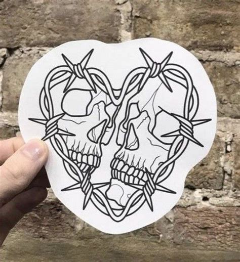 A Hand Holding Up A Sticker With Two Skulls In The Shape Of A Heart