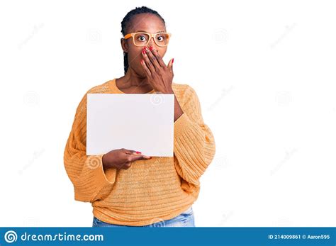 Young African American Woman Holding Cardboard Banner With Blank Space Covering Mouth With Hand