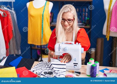 Young Blonde Woman Tailor Smiling Confident Using Sewing Machine At