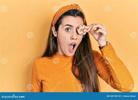 Joven Adolescente De Brunette Sosteniendo Galleta Sobre El Ojo Asustado