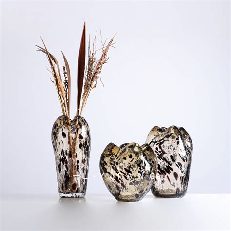 Three Glass Vases With Plants In Them On A White Surface One Is Shaped