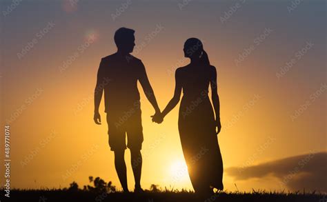 silhouette of couple holding hands walking into the sunset Stock Photo ...