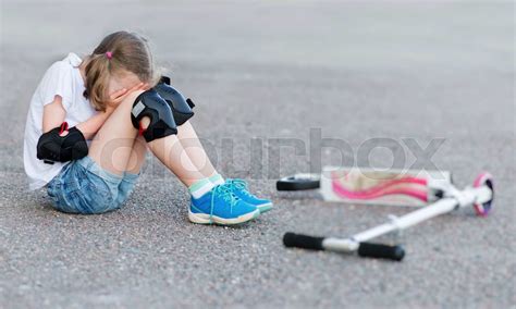 Little girl fell from the scooter on the street. | Stock image | Colourbox