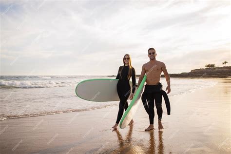 Premium Photo Beautiful Young Couple Walking On Beach With Surfboards