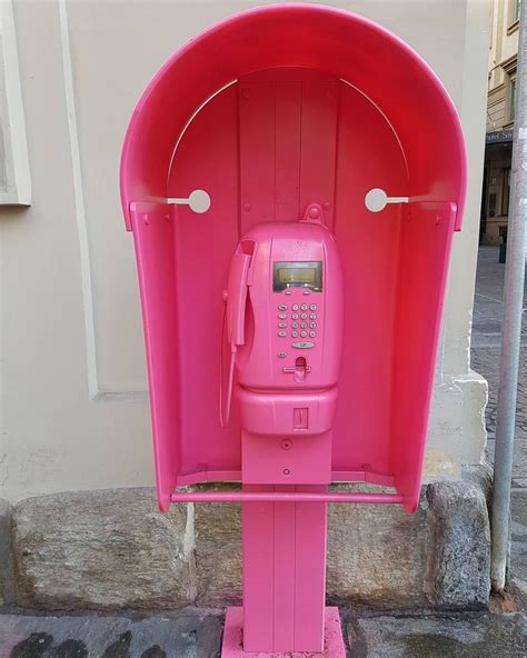 A Pink Phone Booth Sitting On The Side Of A Street