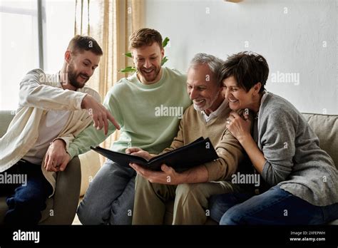 A Gay Couple Sits With Parents Looking At A Photo Album Together Stock Photo Alamy