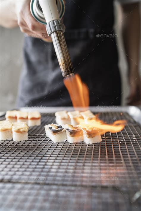 Male Chef Using Culinary Torch On Sushi Pieces Stock Photo By Scopioimages