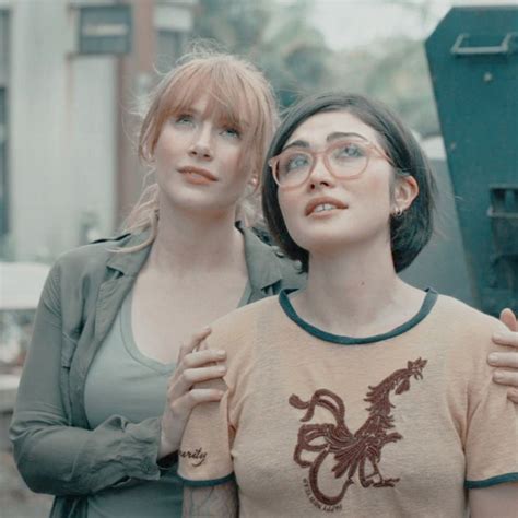 Two Women Standing Next To Each Other In Front Of A Dumpster And