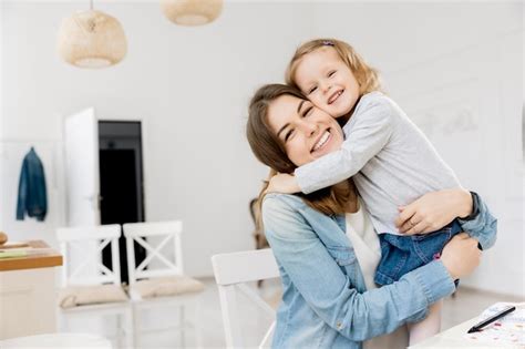 Primer Plano De Una Joven Madre Morena Poniendo Y Sosteniendo A Una