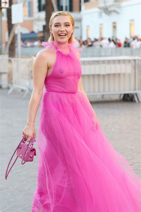 A Woman In A Pink Dress Is Walking Down The Street With Her Hand On Her Hip