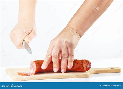 Female Hands With A Knife Sliced Salami On A Cutting Board Stock Image