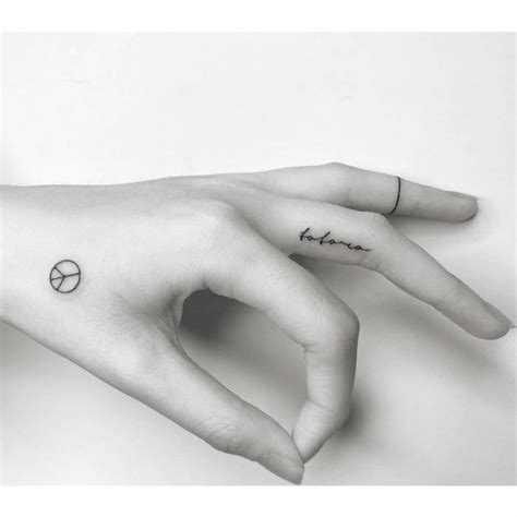 Peace Symbol And Lettering Tattoos Located On The Hand