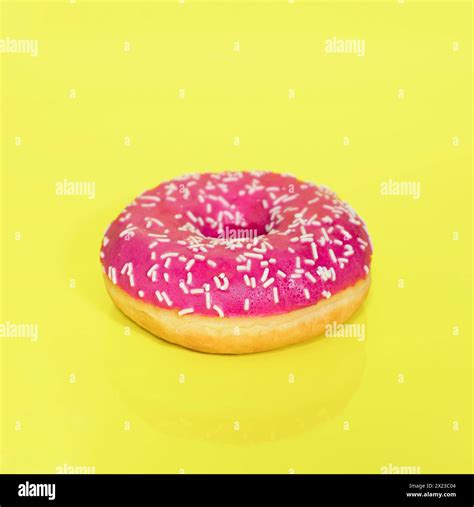 Pink Iced Ring Doughnut With Sprinkles On Taken On A Yellow Coloured