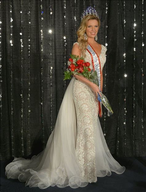 A Beautiful Woman In A Gown And Tiara Standing Next To A Backdrop With