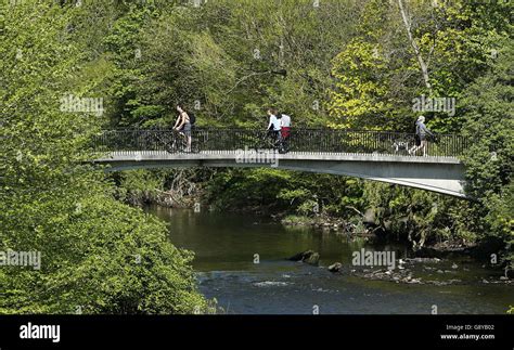 People Travel Across A Bridge Over The River Kelvin In Kelvingrove Park