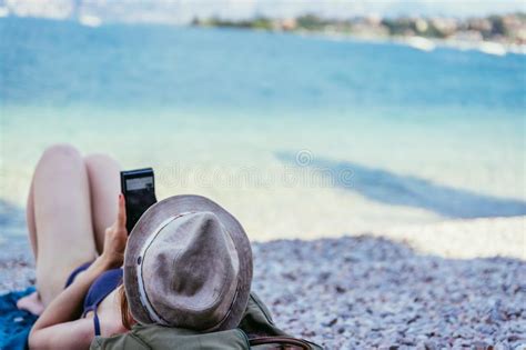 Smartphone Sur La Plage La Belle Jeune Fille Avec Le Chapeau De Paille Dans Le Bikini Se