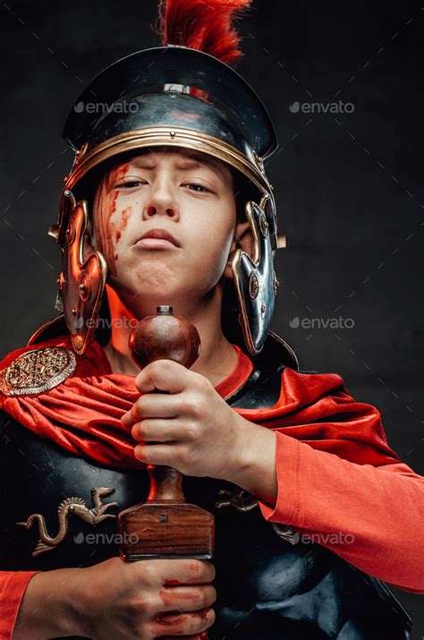 Boy In Dark Armour And Red Cape With Sword In Dark Background Stock