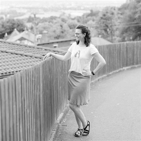 A Woman Leaning Against A Fence With Her Hand On The Top