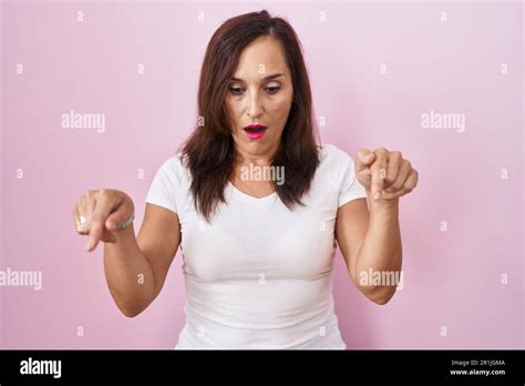 Middle Age Brunette Woman Standing Over Pink Background Pointing Down